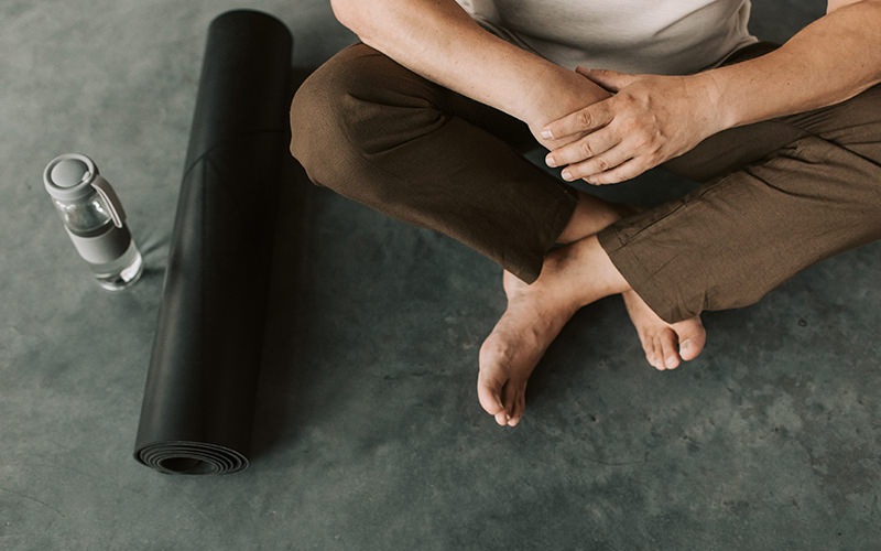 Person sitting with a yoga mat