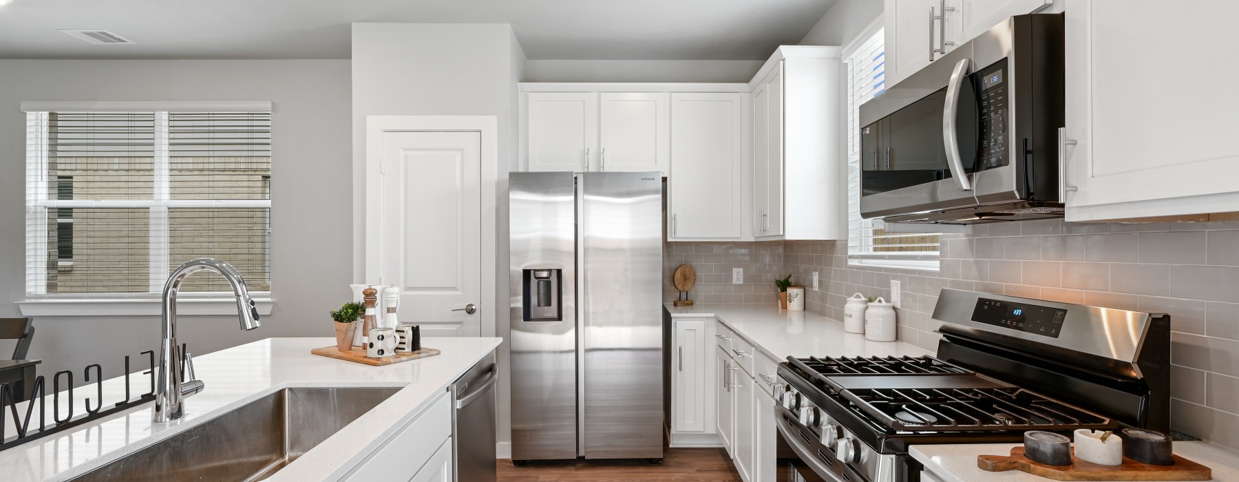 kitchen with stainless appliances, white cabinets, and hardwood floors at Katy Legacy in Katy, Texas