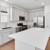 Spacious kitchen that is well lit with wood floors and stainless steel appliances with complete access to the living room 