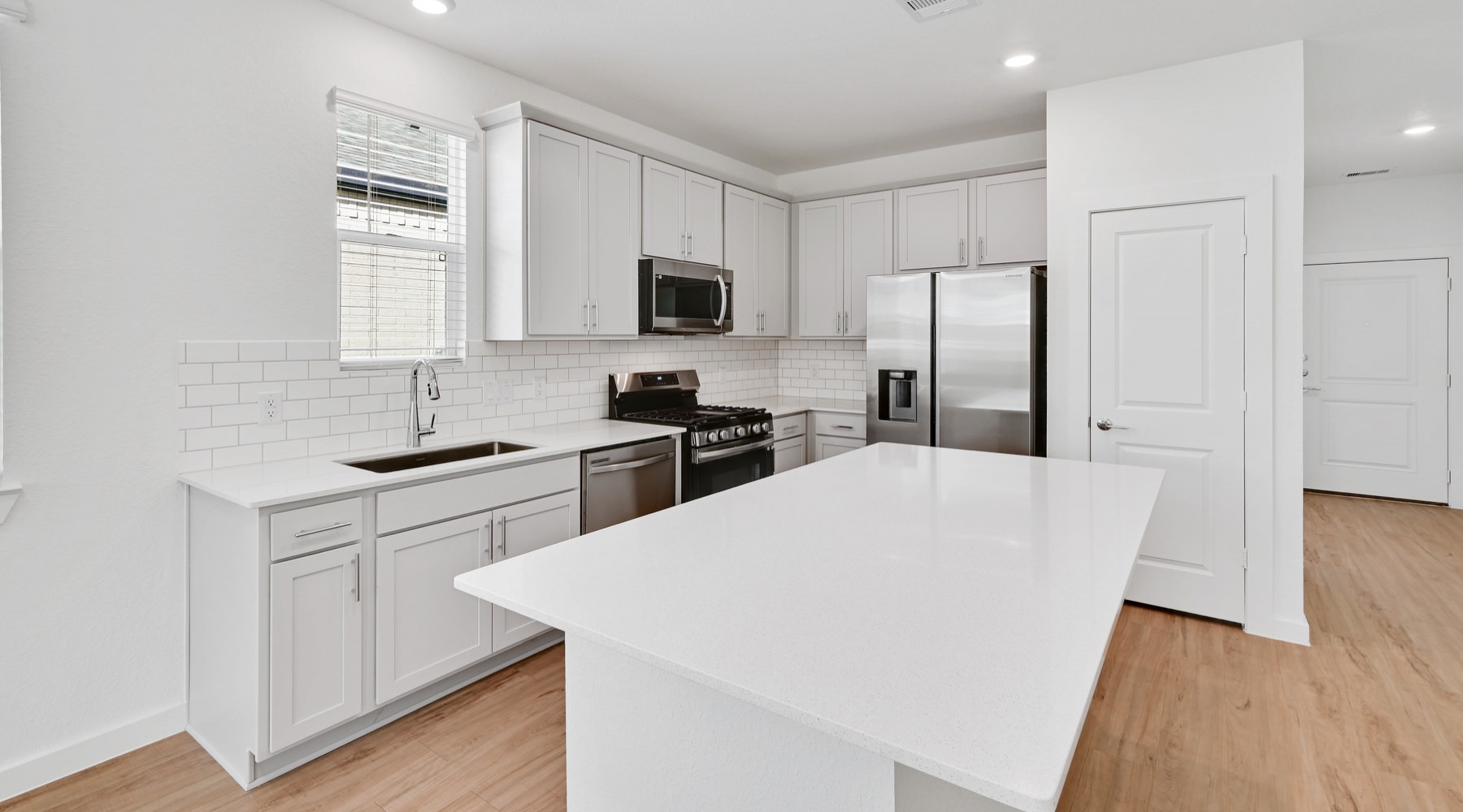 Kitchen Spacious kitchen that is well lit with wood floors and stainless steel appliances with complete access to the living room